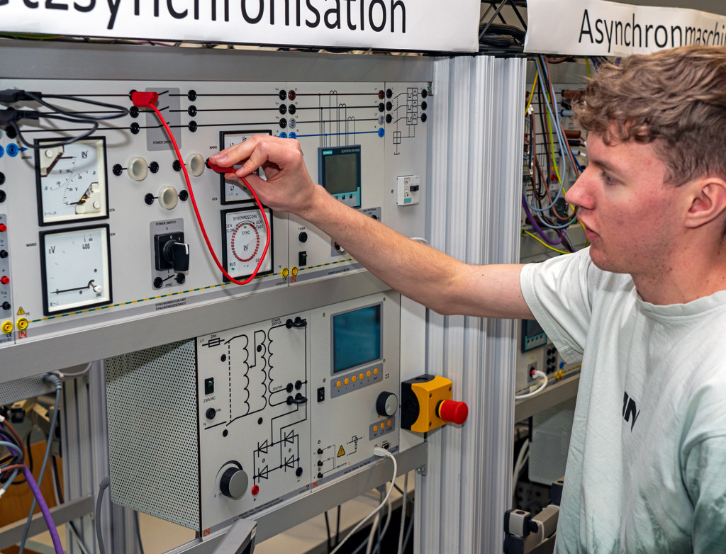 Studierender Jens Hagmeyer steht vor Modell Netzsynchronisation im Labor für Elektrische Systeme