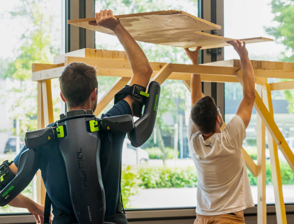 Zwei Studierende arbeiten Überkopf mit Exoskelett