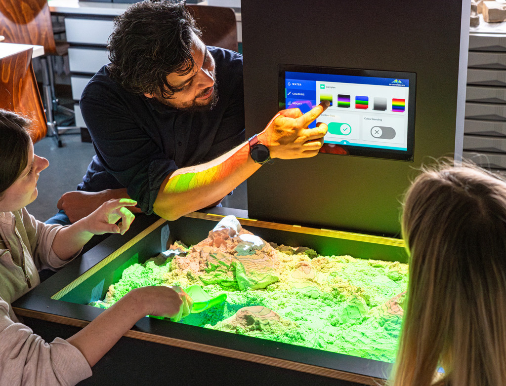 Professor Julius Jara gemeinsam mit zwei Studierenden an der AR-Sandbox