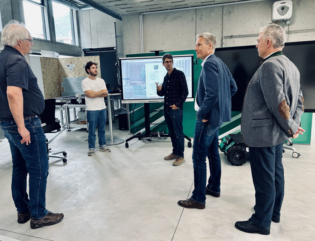 Fünf Männer stehen in einem Raum und diskutieren