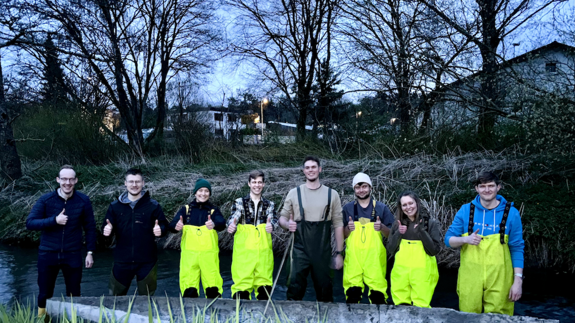Junge Menschen stehen in einem Bach mit Betonkanu